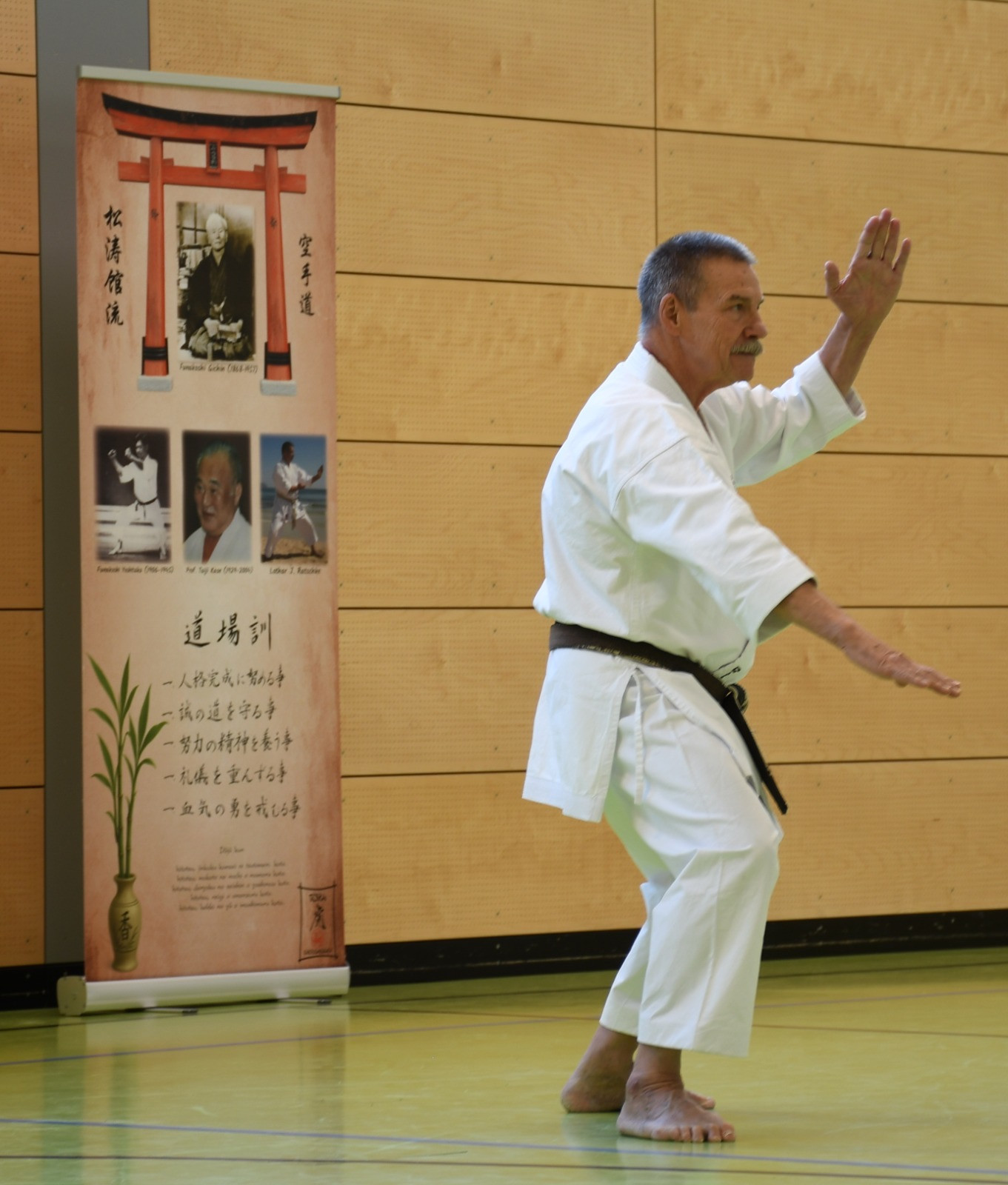 Kyoshi Lothar J. Ratschke bei einer Karate-Vorführung neben dem vollständig sichtbaren Rollup zur Karate-Tradition